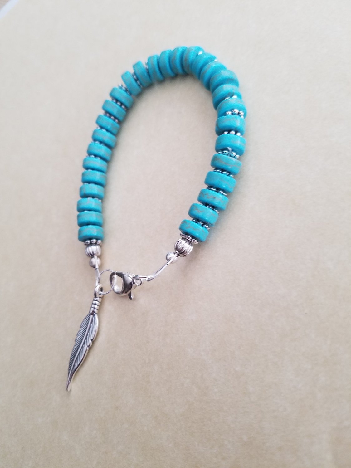 Turquoise rondelle  beads with a silver plated feather.