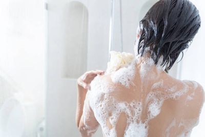 Köperpflege, eingeseifter Frauen Rücken. Mit einen Schwamm in der Hand.