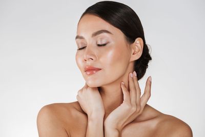 Gesichtspflege, Frauen Gesicht, dunkelbraune Haare, beide Hände um den Hals.