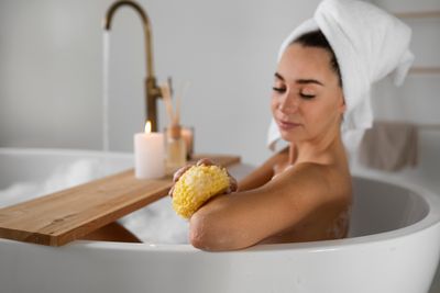 Duschen und Baden, Frau in der Badewanne  mit Schwann in der Hand.