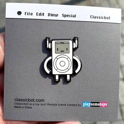A beautiful enamel pin on a backing card. The pin shows the iBoy character that looks like a classic MP3 player. 