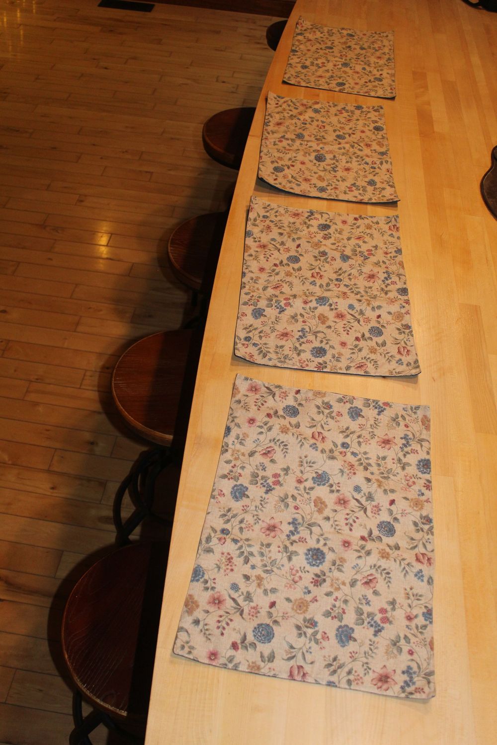 Handmade floral placemat set arranged on wooden dining table with chairs