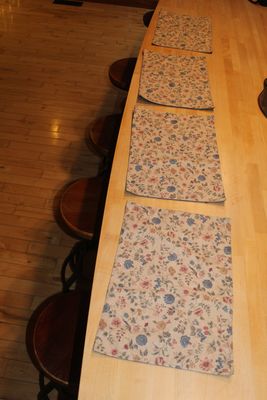 Handmade floral placemat set arranged on wooden dining table with chairs