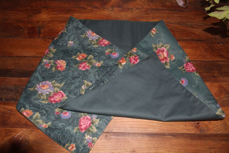 Handmade reversible floral table runner in green with rose print on wooden table