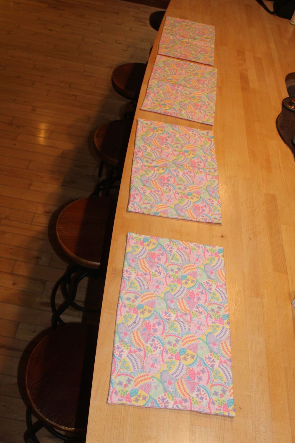 Set of Easter egg placemats with pastel spring colors arranged on a wooden table.