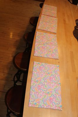 Set of Easter egg placemats with pastel spring colors arranged on a wooden table.