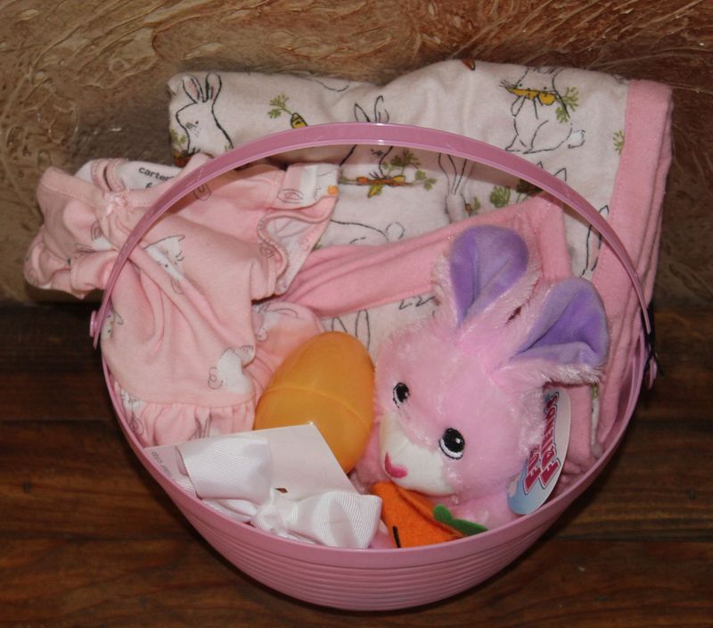 Pink baby Easter basket gift set with bunny plush, baby clothes, bow, and Easter egg