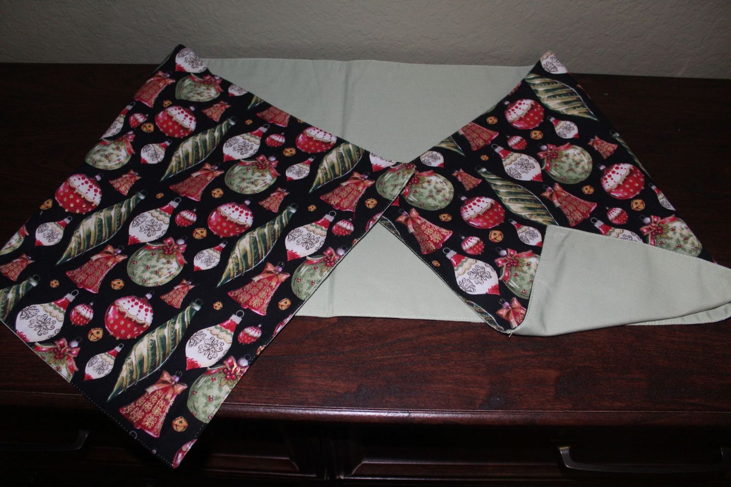Holiday table runner featuring festive ornaments and solid pastel green fabric reverse side