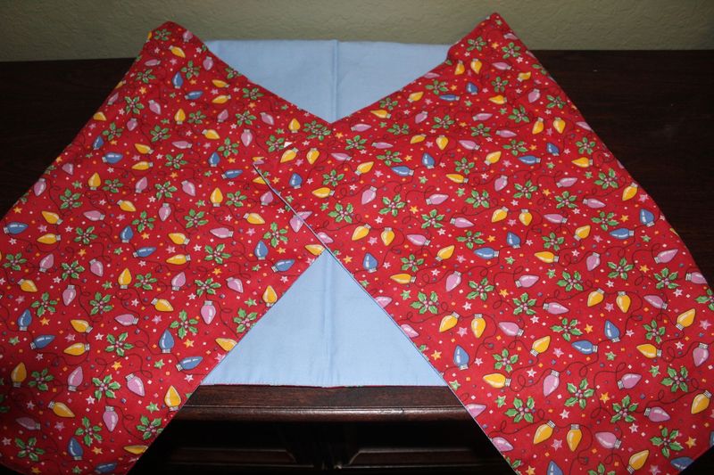 Handmade reversible Christmas table runner featuring red fabric with colorful holiday lights and pastel blue backing