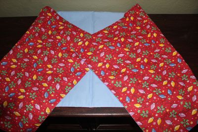 Handmade reversible Christmas table runner featuring red fabric with colorful holiday lights and pastel blue backing