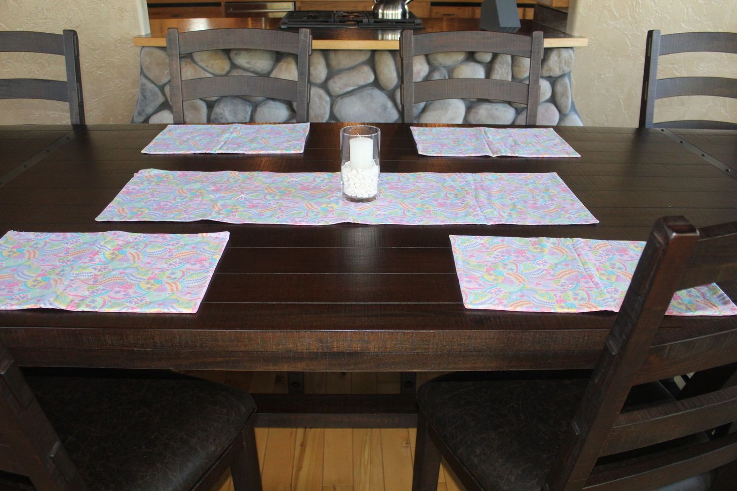 Easter dining table arrangement with pastel egg pattern placemats and table runner.