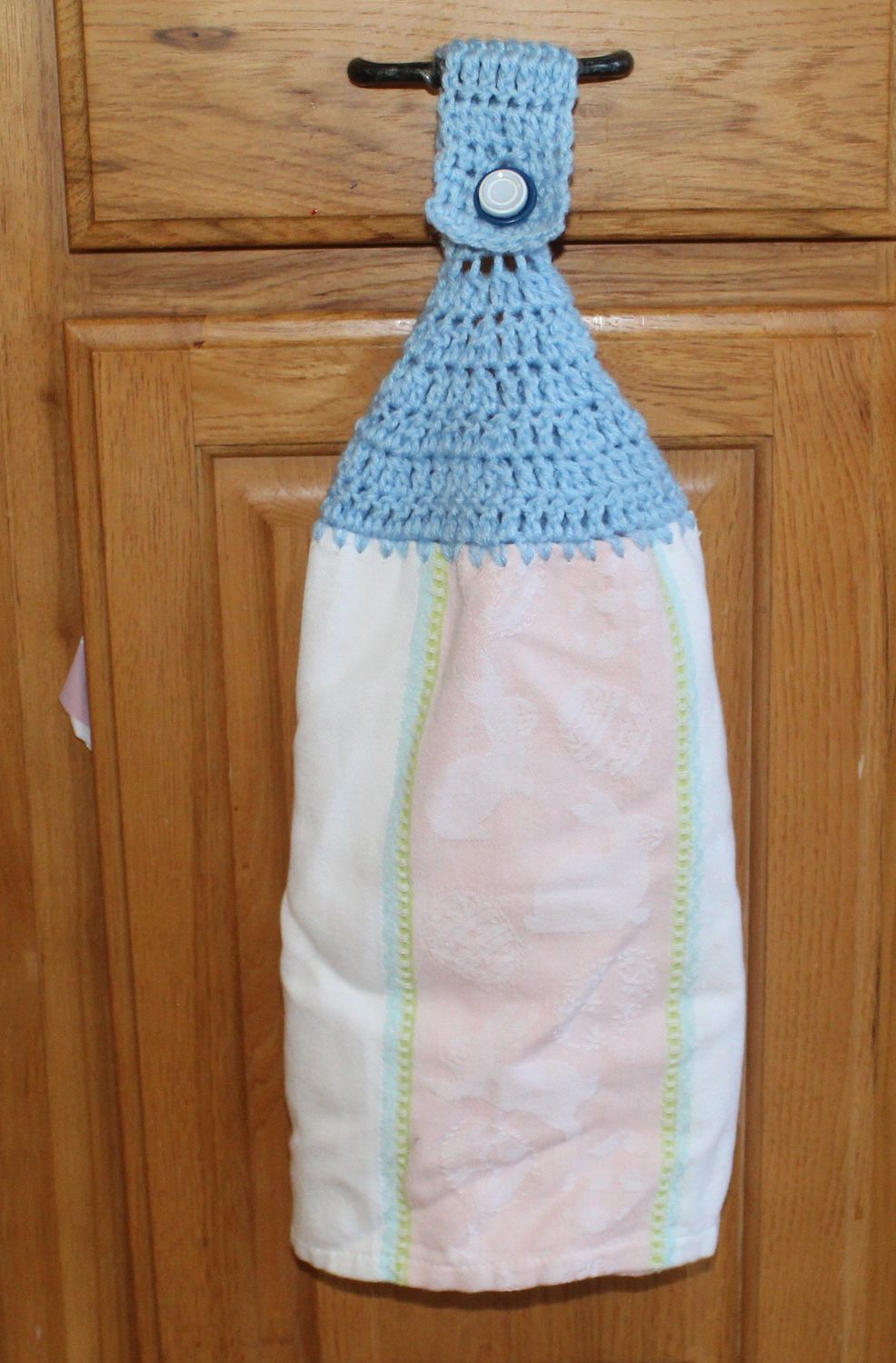 Decorative kitchen hand towel with blue crochet topper and soft pink center stripe.