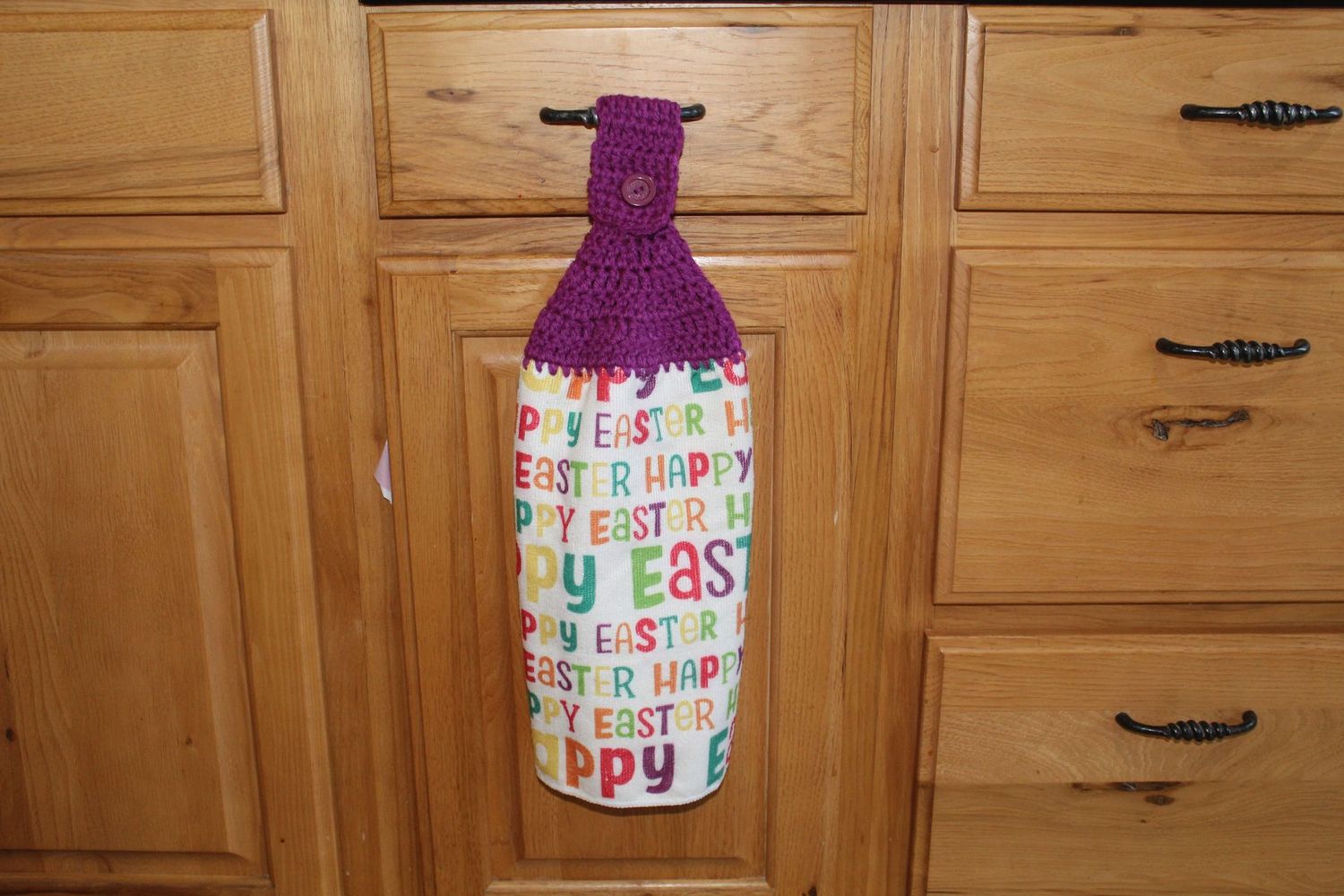 Handmade Easter kitchen towel with colorful “Happy Easter” print and purple crocheted topper to hang.