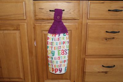 Handmade Easter kitchen towel with colorful “Happy Easter” print and purple crocheted topper to hang.