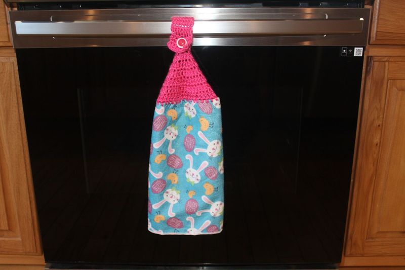 Festive Easter kitchen towel with pink crochet holder and bunny, chick, and egg pattern.