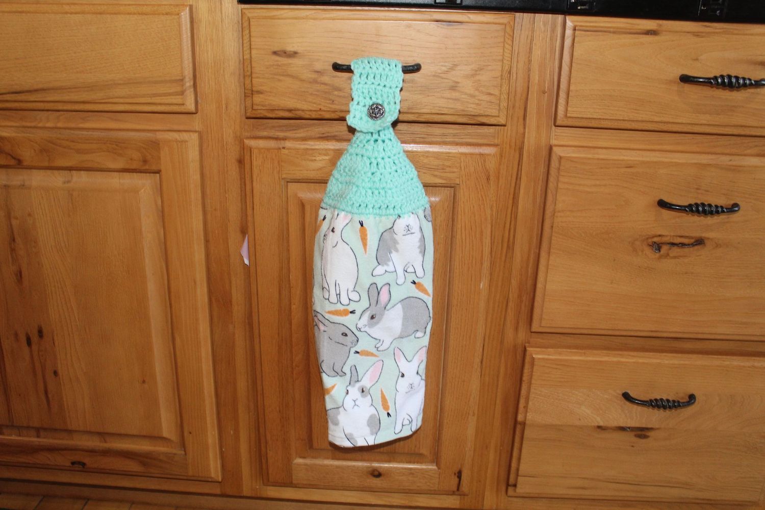 Easter themed hanging kitchen towel with multiple bunny illustrations and mint crochet holder.
