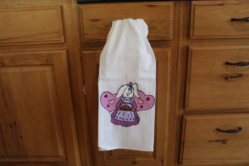 Hand painted Easter bunny kitchen towel with rabbit holding pie and pink heart background.