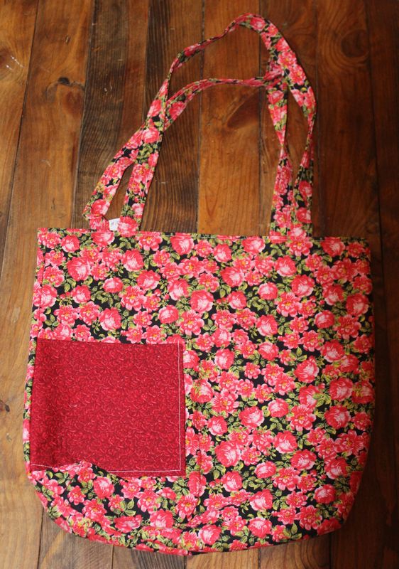 Handmade red rose floral tote bag with front pocket on black background fabric.