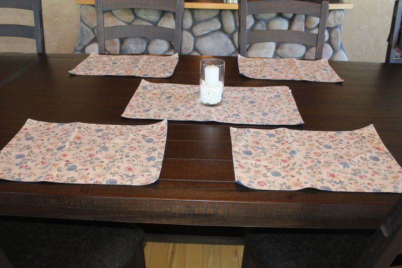 Handmade floral placemats and table runner set displayed on dark wood dining table