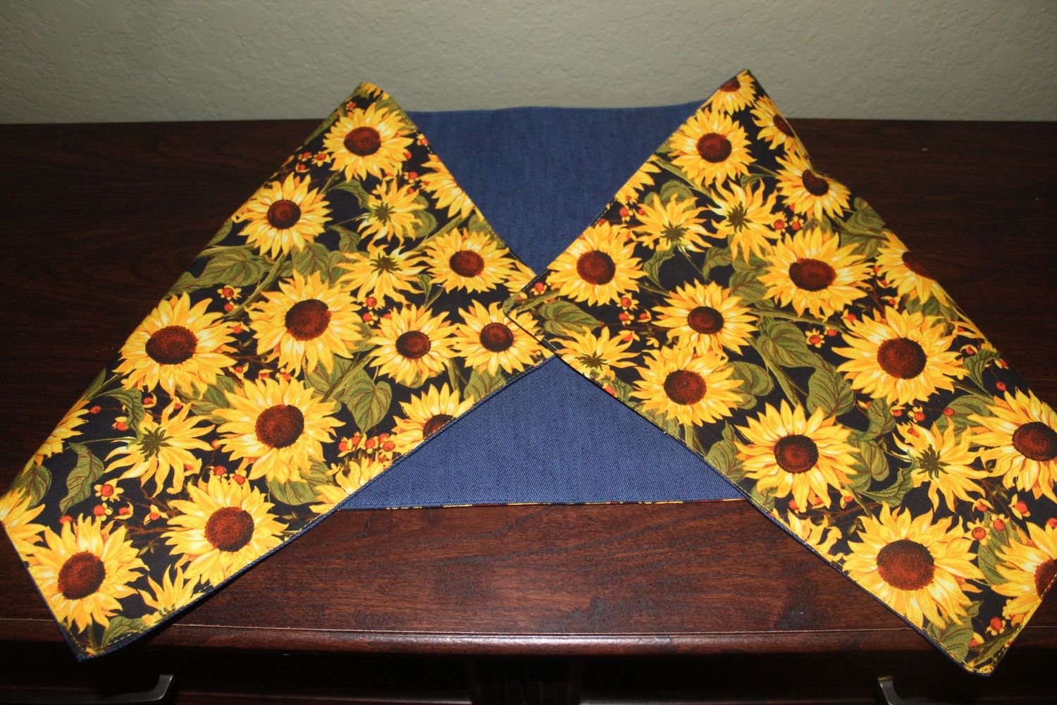 Handmade sunflower reversible table runner with yellow floral print on dark background displayed on wooden table