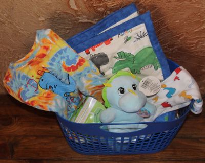 Handmade dinosaur boy gift basket with tie dye shirt, plush dinosaur toy, toddler baby blanket, and sippy cup