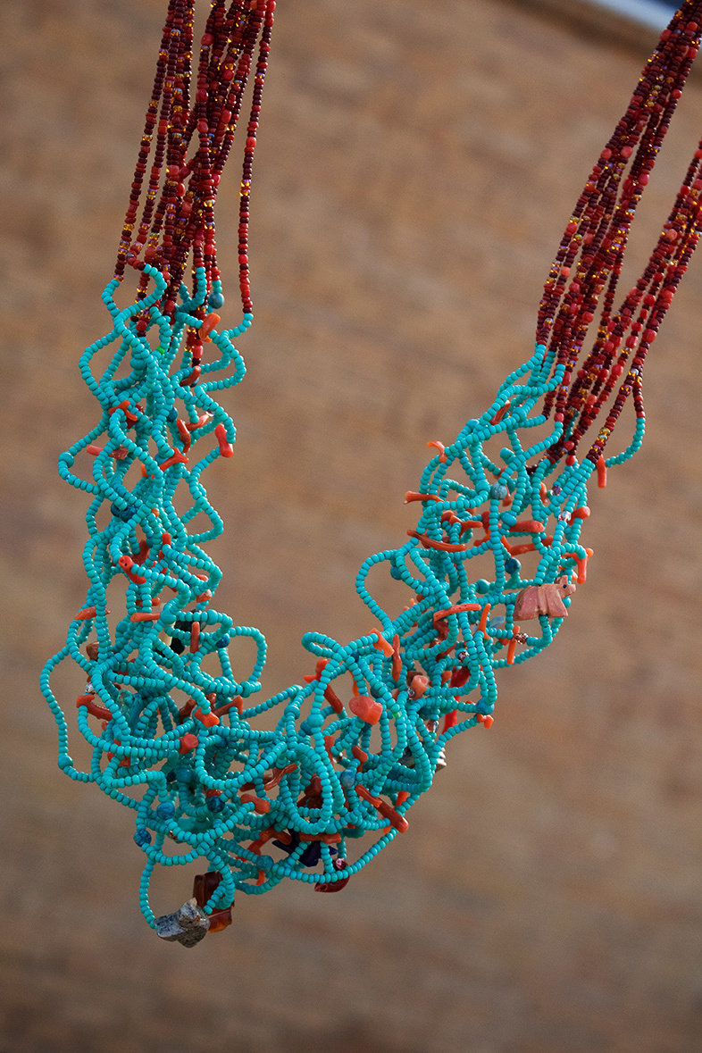 Multiple strands of turquoise and orange and brown seed beads on curly wire, tiny carved stone animal figures, sterling findings and clasp