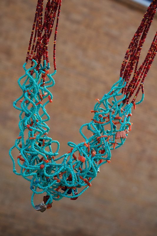 Multiple strands of turquoise and orange and brown seed beads on curly wire, tiny carved stone animal figures, sterling findings and clasp