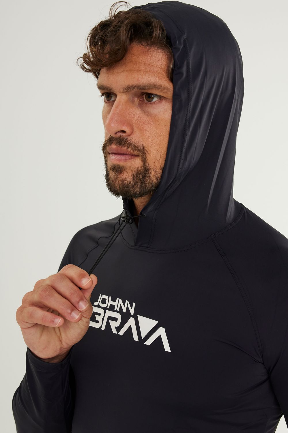 Man wearing Johnn Brava black hooded lycra top with UV protection while surfing