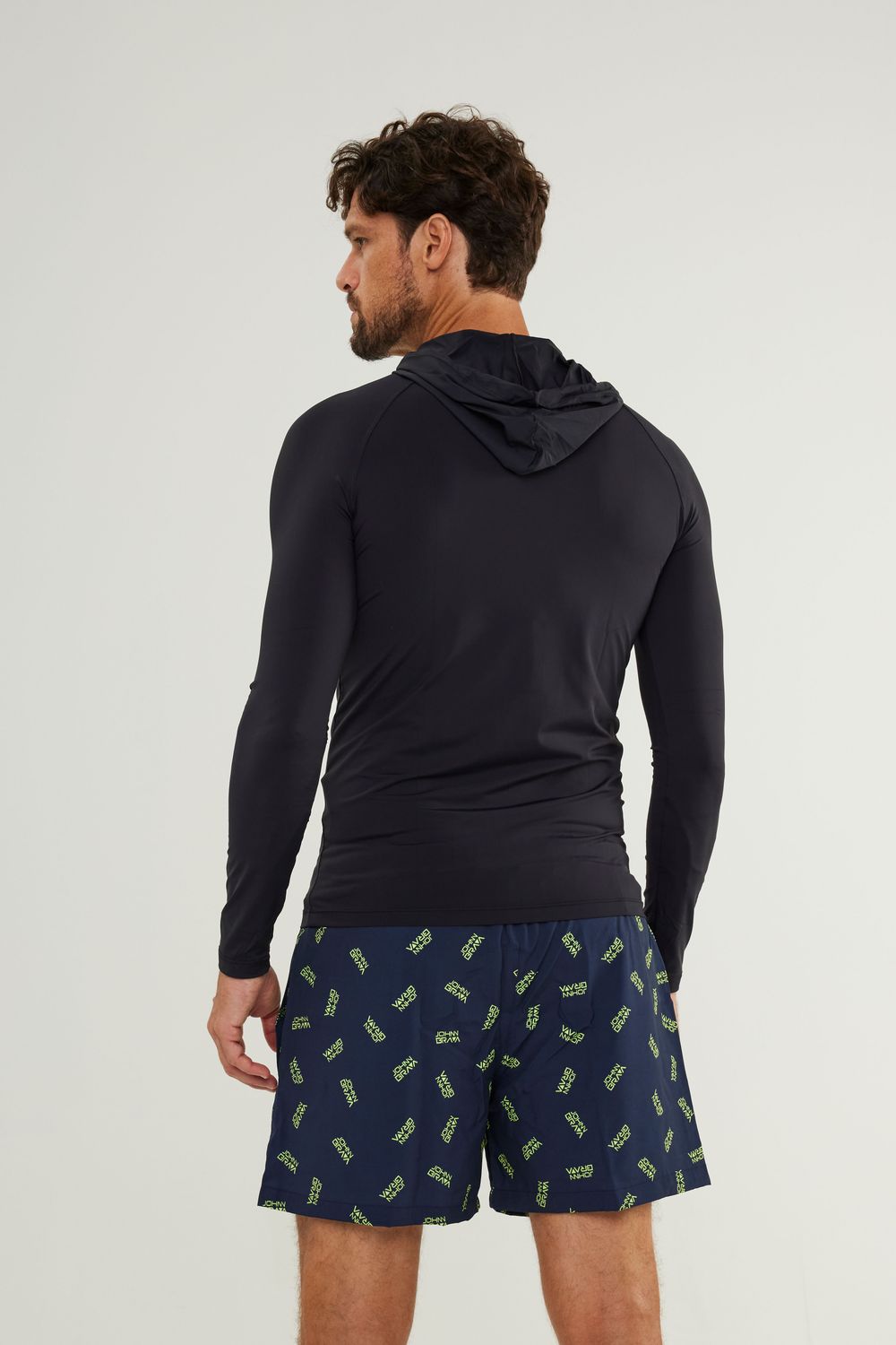 Man wearing Johnn Brava black hooded lycra top with UV protection while surfing - view 2