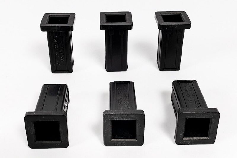 sechs schwarze Kunststoff Sitzbuchsen in quadratischer Form mit leicht erhabener Mitte