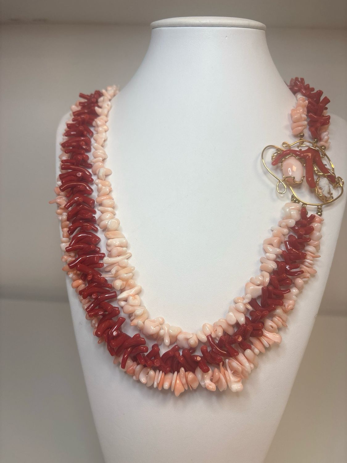 Collana formata da tre fili di corallo, due in corallo orientale rosa, uno in corallo Mediterraneo e centrale in argento 925 bagnato in oro, con ramo di corallo e  cameo di conchiglia,
