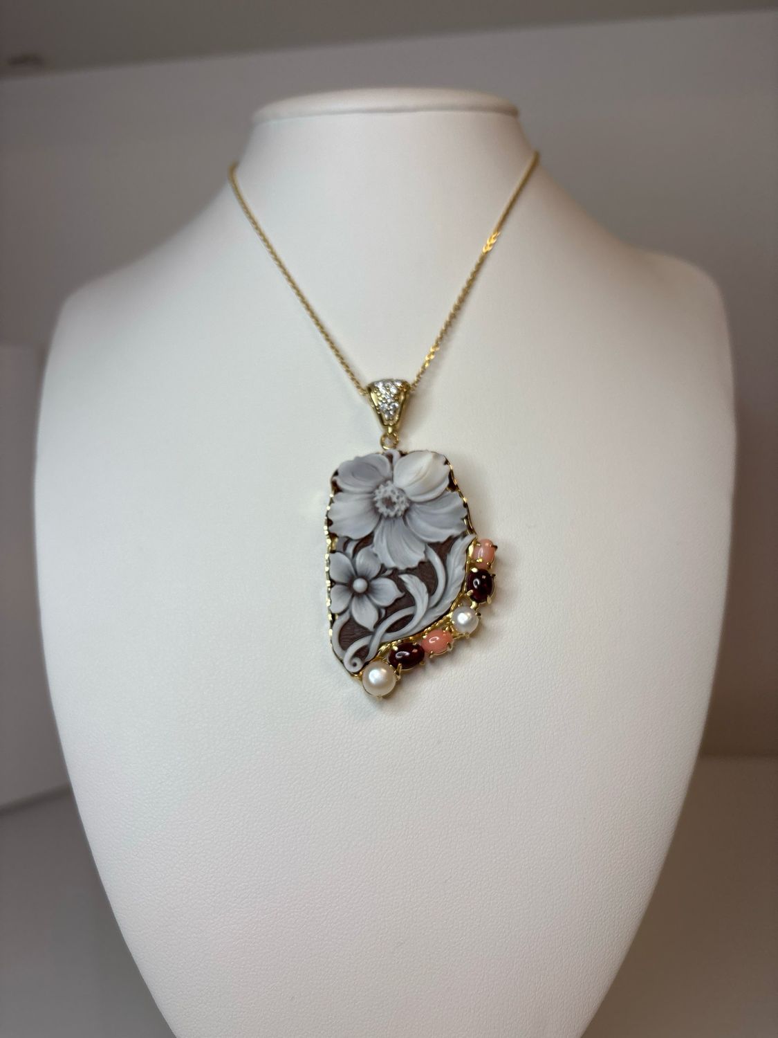 Cameo di conchiglia sardonico inciso a mano di centimetri 5 × 3 circa con struttura totalmente in argento 925  placcato in oro, impreziosito da zirconi, perle , Granati  e corallo rosa orientale.