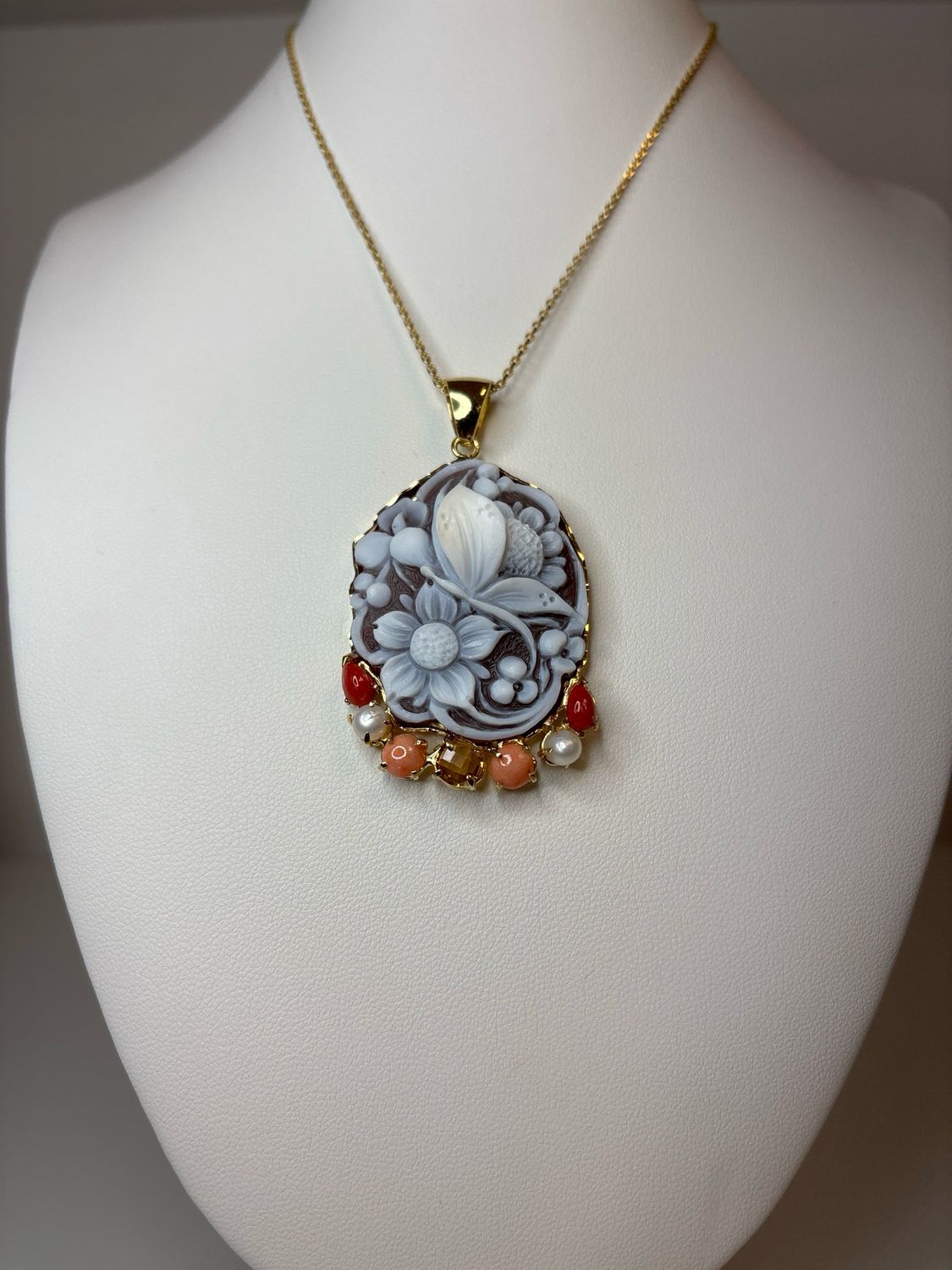 Cameo di conchiglia sardonico montato su struttura in argento 925 placcata oro e impreziosito con perle coralli e topazio sfaccettato.