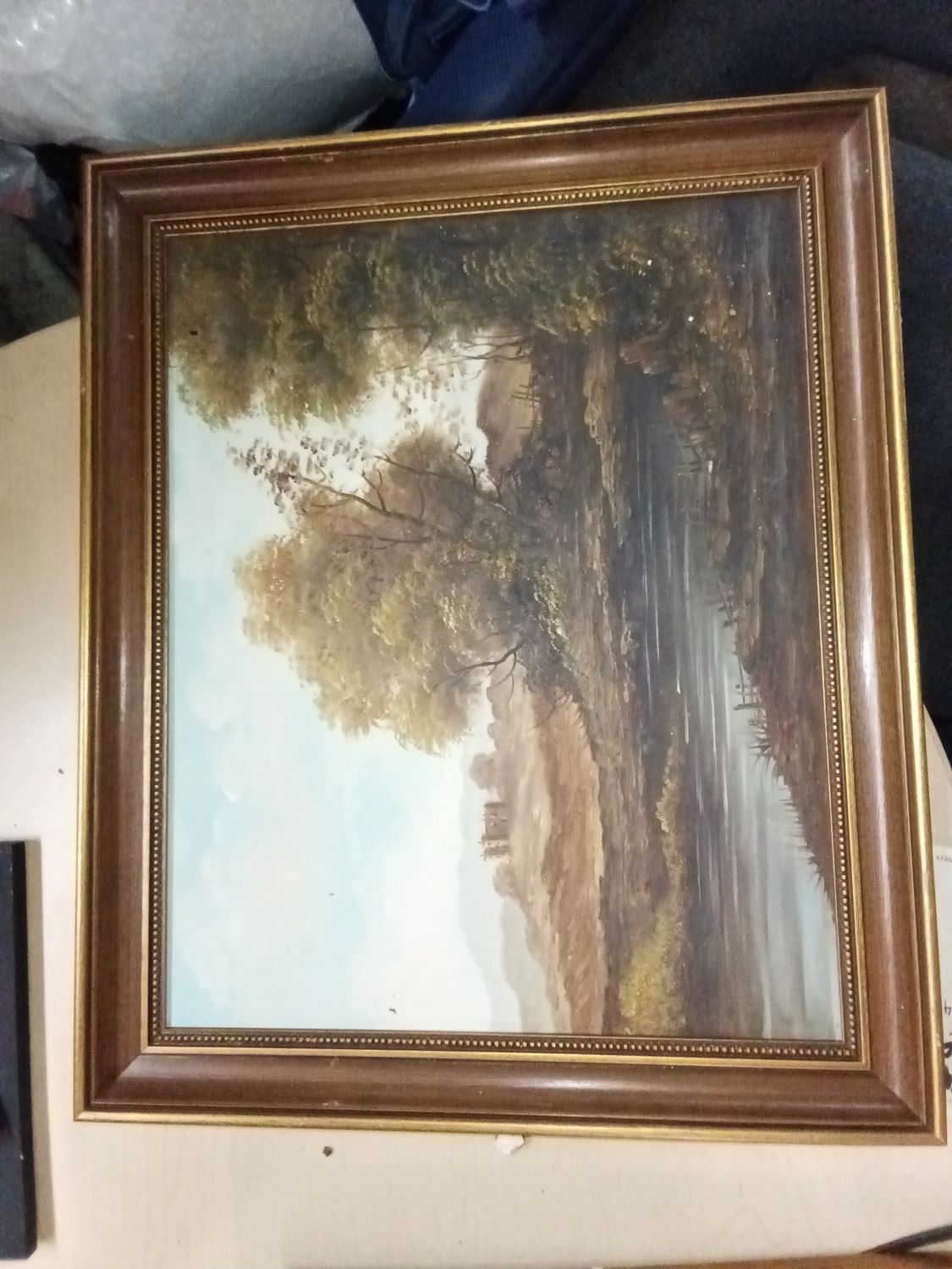 The piece features a scene with trees, a river, and a distant cottage.
