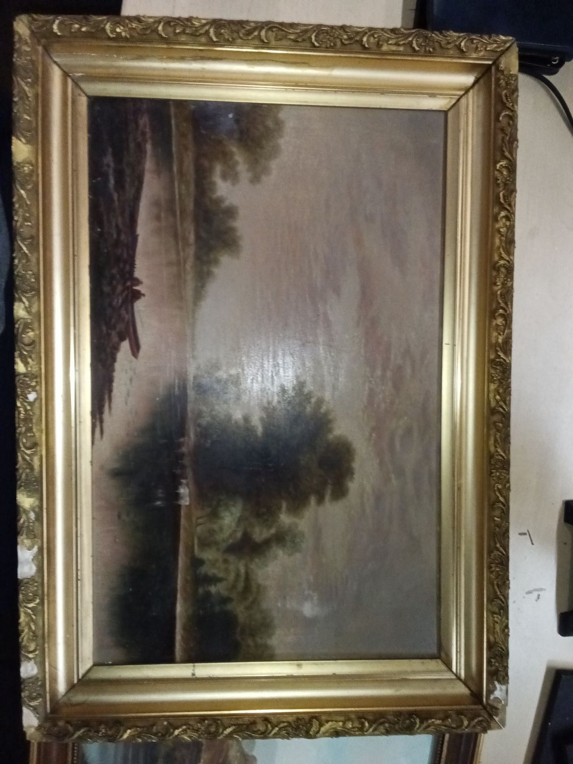 19th-century oil on canvas landscape painting featuring a waterway and tree scene.It is housed in an ornate gold-gilt wooden frame that shows signs of minor damage, such as missing pieces.