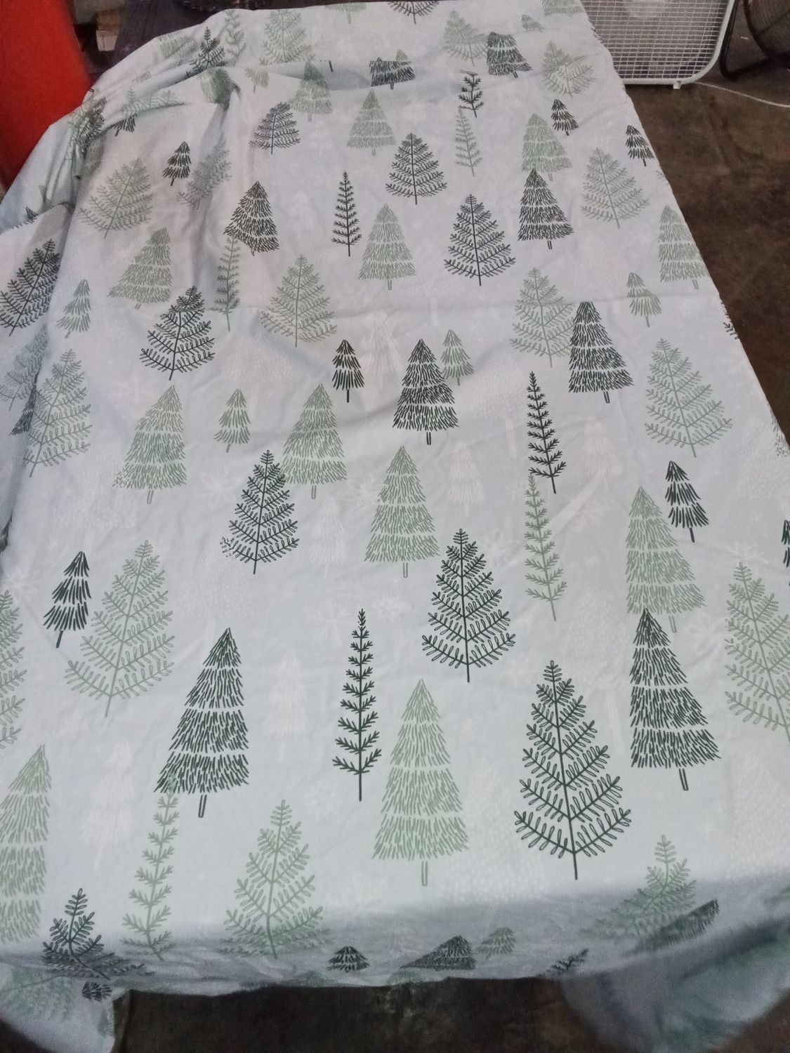 Blue shower curtain with white, light green and dark greeng trees with snowflakes