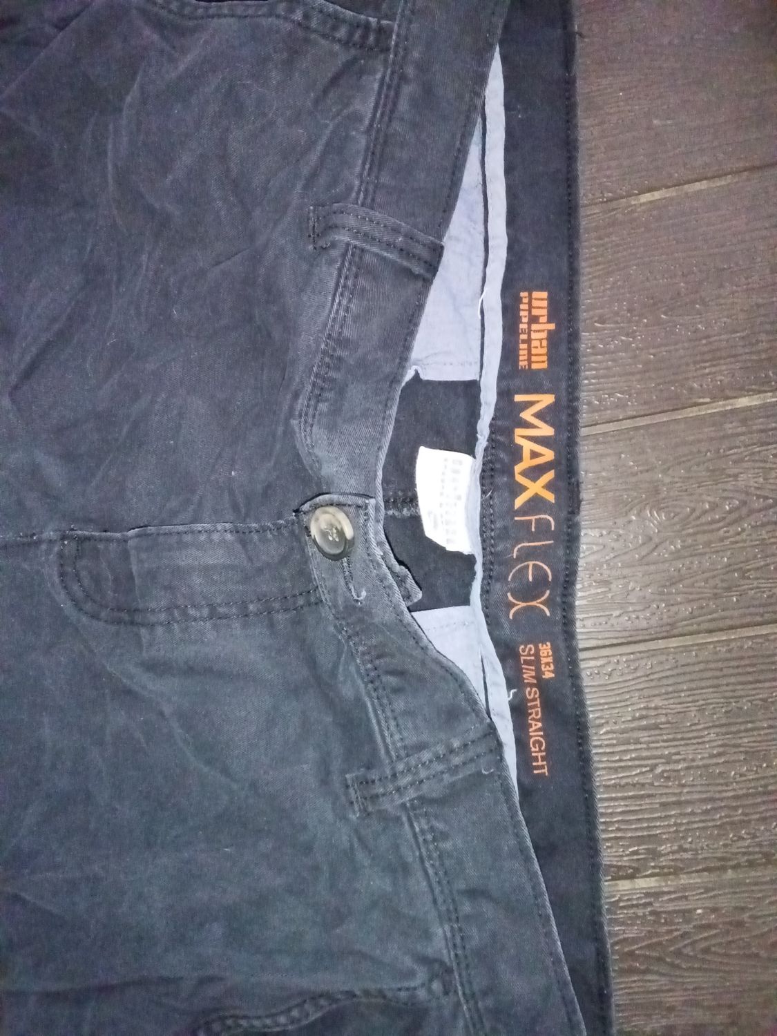 black Urban Pipeline MaxFlex slim straight jeans, featuring prominent orange branding on the inner waistband. Size 36x34