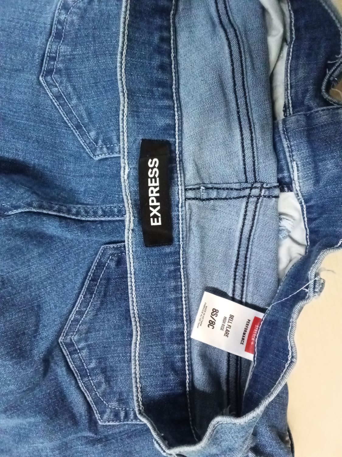 Express bell flare jeans feature a high-rise fit and are constructed from stretch performance denim. The size 8S/8C indicates a Size 8 Short / 8 Curvy fit