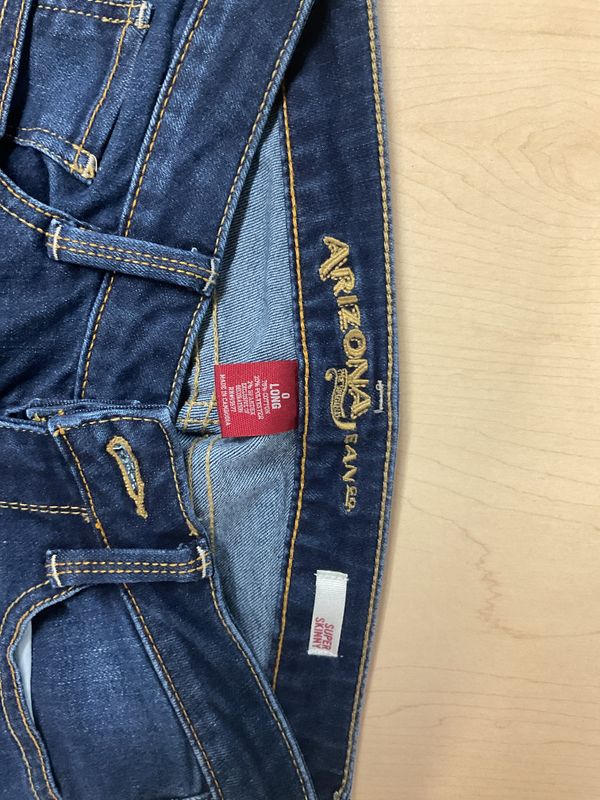 Arizona Jean Co. "Super Skinny" denim jeans in a classic dark wash, featuring whiskering at the hips and traditional contrast topstitching. They are designed with a classic five-pocket layout and mid-