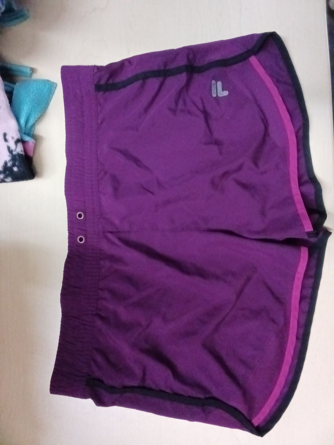 Deep purple Fila athletic shorts featuring a contrasting magenta inner waistband and a subtle white logo near the hem.