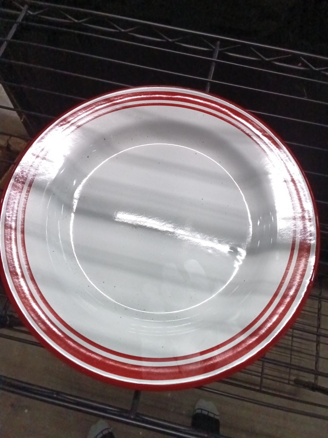 white round dinner plate featuring a distinctive red-banded rim pattern.