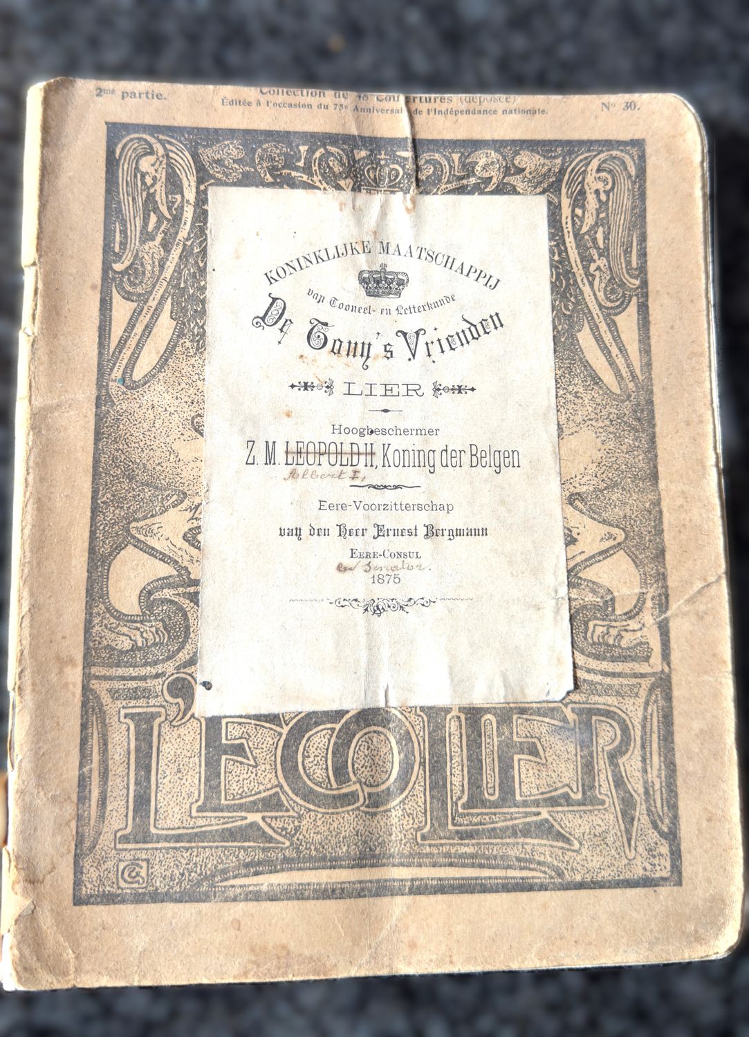 ​Handgeschreven toneelmanuscript “Een Schat van eene Vrouw” – H. Van Peene – in nationale omslag “L’Écolier” met opgekleefd ceremonieel blad van De Tony’s Vrienden –1875