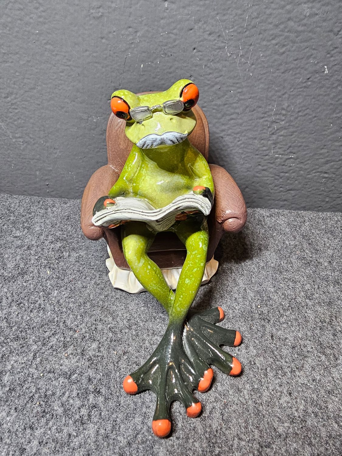 Żaba w fotelu czytająca gazetę