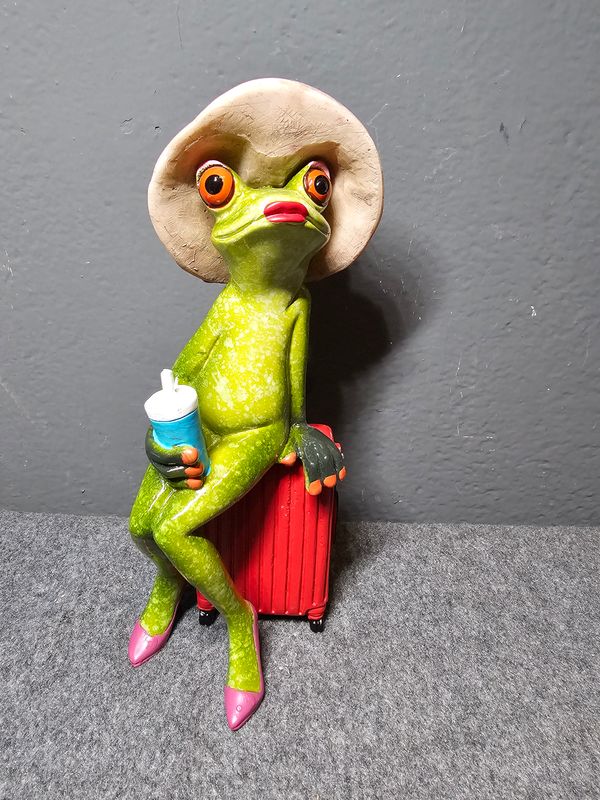 Żabka w kapeluszu siedząca na walizce