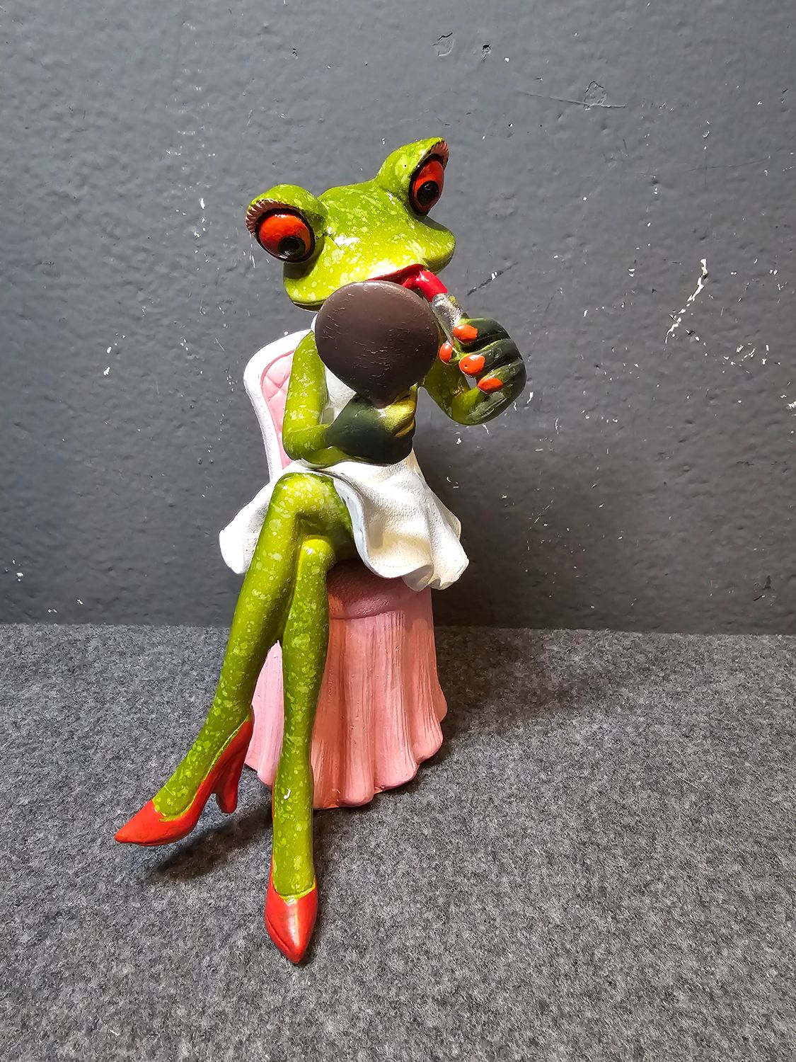 Żaba robiąca makijaż na różowym fotelu