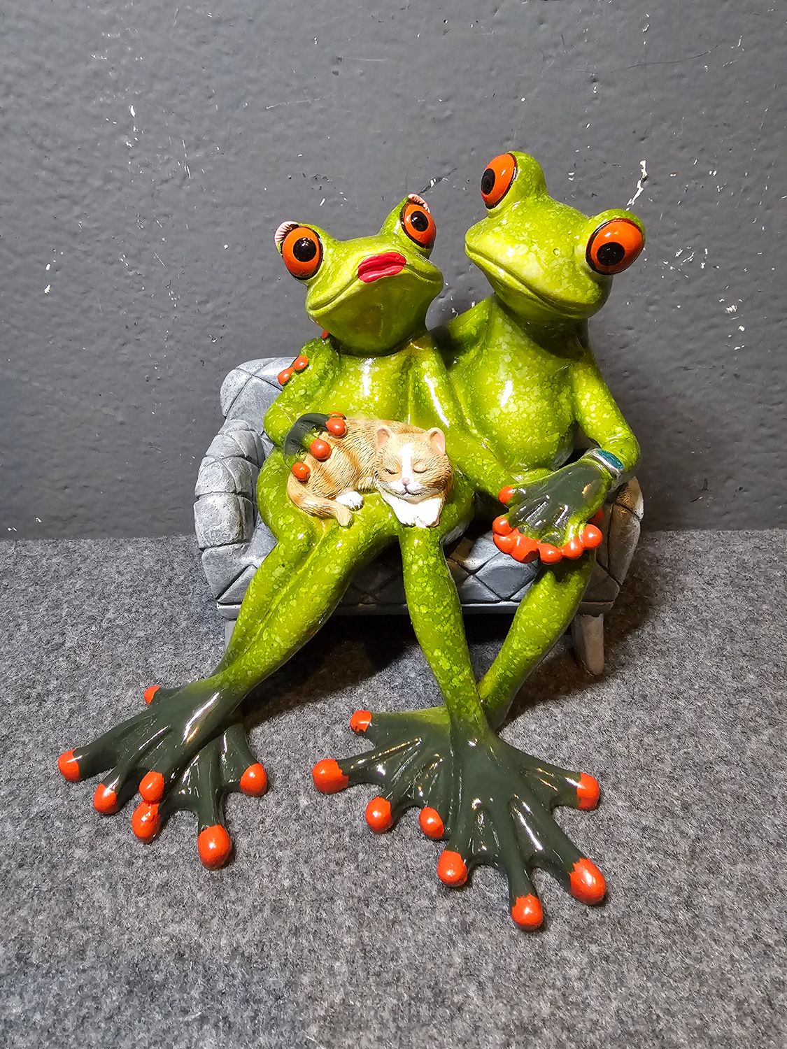 Żaba para siedząca na sofie z rudym kotkiem na kolanach