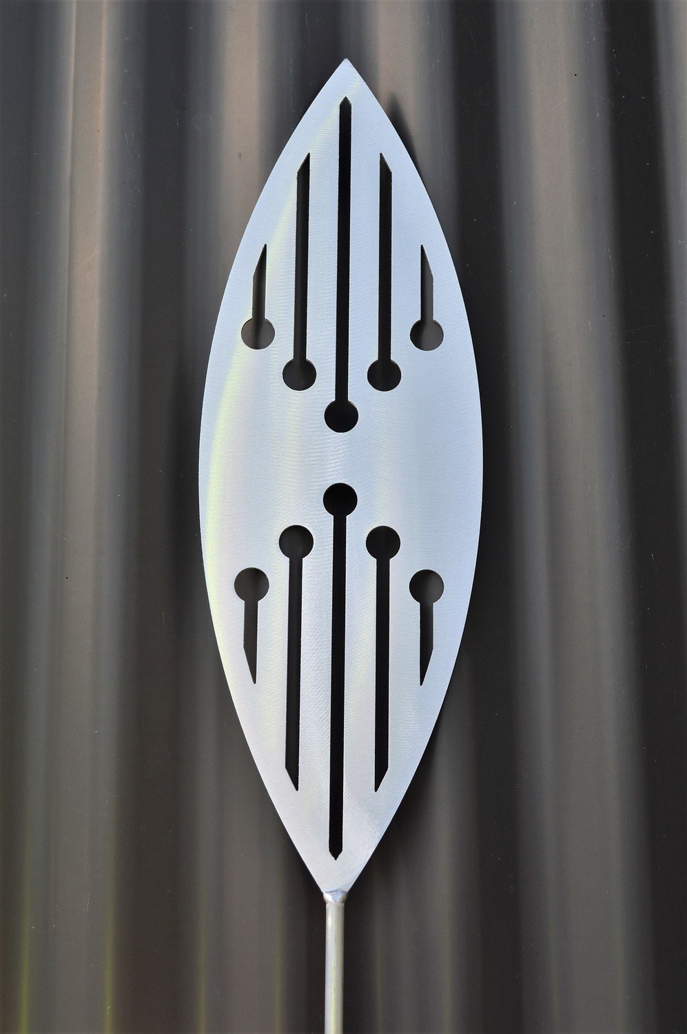 Reflection Aluminium Spear by Grounded Art NZ &amp; a dark clad building. The bright metal art pops against the dark background.