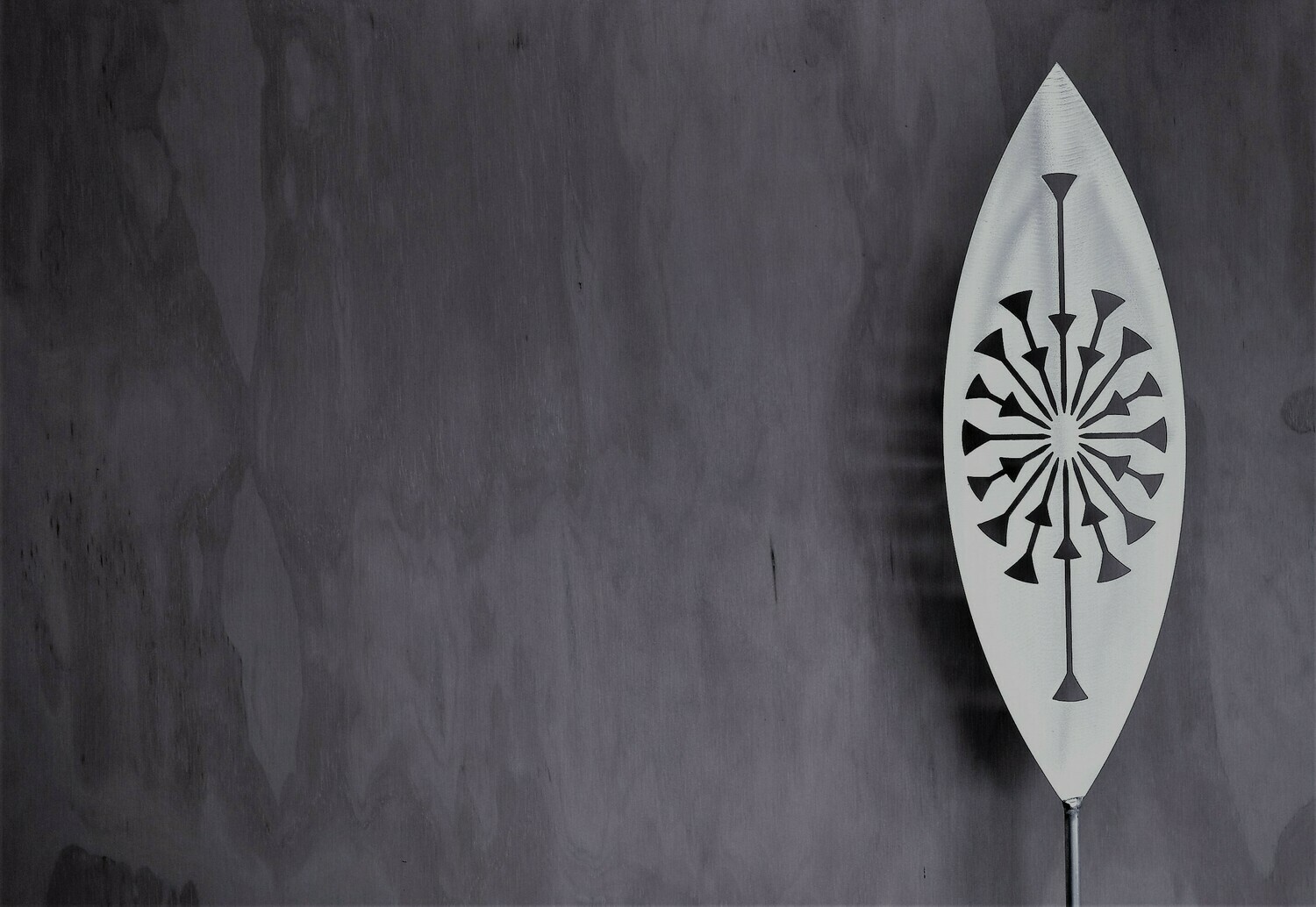 Tohu Aluminium Spear by Grounded Art NZ in a gallery setting where the shadows are cast onto the pale plywood wall behind.