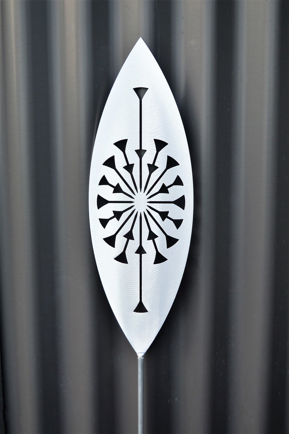 Tohu Aluminium Spear by Grounded Art NZ and a dark clad building. The bright metal art pops against the dark background.
