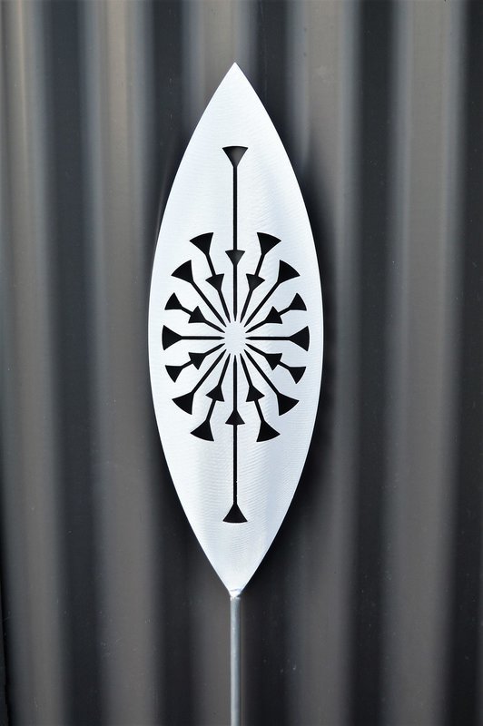 Tohu Aluminium Spear by Grounded Art NZ and a dark clad building. The bright metal art pops against the dark background.